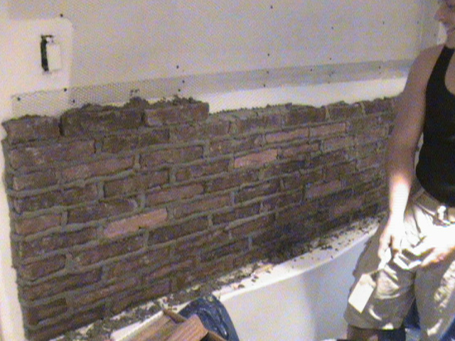 Masonry workers laying brick in bathroom.