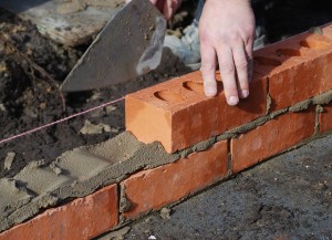 A masonry worker laying brick.