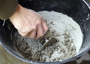 Worker mixing concrete in bucket