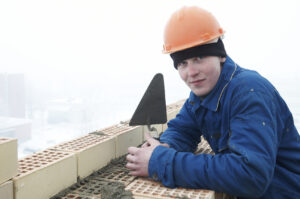 A brick layer worker building a brick wall at construction site