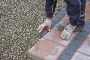 worker lays brick pavers along the sidewalk